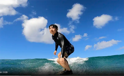 ハワイの海でロングボードに立って波に乗る生徒。CLIPSハワイの初心者向けサーフレッスンで撮影されたアクション動画